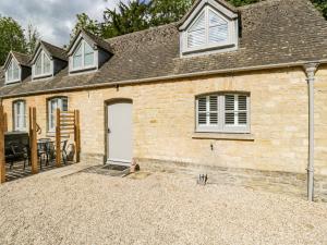 ein Backsteinhaus mit einer weißen Tür und einer Terrasse in der Unterkunft The Coach House in Tetbury