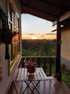 eine Vase auf einem Tisch auf einem Balkon mit Blick auf den Sonnenuntergang in der Unterkunft Sítio Juara in Santa Teresa