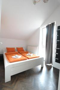 Cama blanca con sábanas naranjas en una habitación con ventana en Hostel Fair and Square en Belgrado
