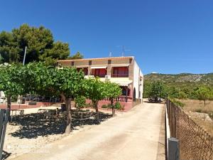a building with trees and a fence next to a road at Hotel Serra D'írta in Alcossebre