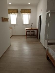 ein leeres Zimmer mit einem Tisch und zwei Fenstern in der Unterkunft Mirador de Trafalgar Conil in Conil de la Frontera