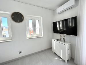 a white room with a clock and a refrigerator at Nancy Apartment - Near Vilamoura Marina by HD PROP in Vilamoura