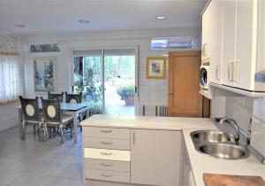 Una cocina con fregadero y una mesa con sillas. en Casa con terrazas, en Zaragoza