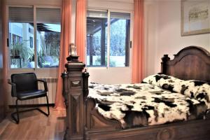 a bedroom with a bed and a chair and windows at Casa con terrazas in Zaragoza