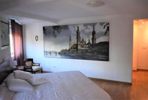 Un dormitorio con una cama y un cuadro en la pared. en Casa con terrazas, en Zaragoza 15 fotos más