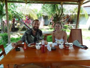 a man and a woman sitting at a table with food at Hostal Bullshark in Cuatro Esquinas