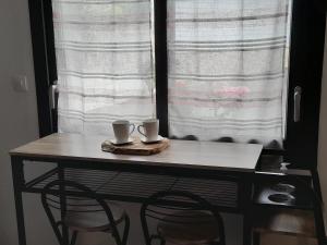 a table with two cups on top of it in front of a window at Les Fines Bulles & spa in Bourseville