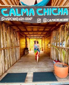 a woman walking down a wooden hallway with a sign at Calma Chicha in Santa Marta