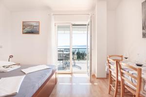 a room with a bed and a table and a balcony at Apartments Tomic in Duće