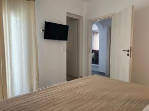 Un dormitorio con una cama con un televisor de pantalla plana en la pared. en Villa stou Chiou, en Agia Anna de Naxos
