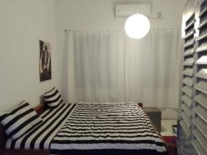 ein Schlafzimmer mit einem Bett mit einer schwarz-weißen gestreiften Decke in der Unterkunft Ezime Guesthouse And Pizzeria in Ada