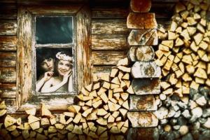 uma fotografia de uma noiva e um noivo a olhar pela janela de uma cabana de madeira em Gospodarstwo Gościnne Racibór em Świętajno