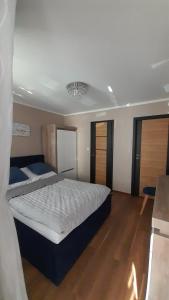 1 dormitorio con 1 cama blanca grande y suelo de madera en Kwatery prywatne en Międzyzdroje