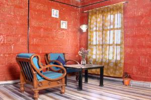 Habitación con sillas, mesa y pared de ladrillo rojo. en SiddhaDham - Farm Stay Cottage 1 en Nashik