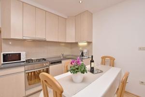 a kitchen with a table with a vase of flowers on it at Apartment Mate in Omiš