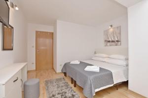 een witte slaapkamer met een bed en een tafel bij Apartment Mate in Omiš