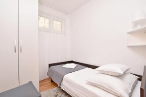a white bedroom with a bed and a window at Apartment Mate in Omiš