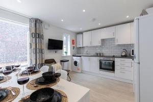 a kitchen with white cabinets and a table with wine glasses at Modern Four Bedroom Four Bathroom Home in Cheltenham