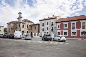 un estacionamiento con autos estacionados frente a un edificio en Apartamentos La Quinta, en Burgos