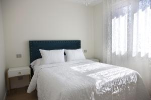 sypialnia z białym łóżkiem i oknem w obiekcie Apartamentos La Quinta w mieście Burgos