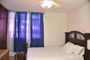 um quarto com uma cama e cortinas azuis em The president room 5 minutes to Devon House 6 strathairn Avenue Kingston em Kingston