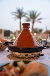 una olla marrón sentada sobre una mesa con comida en RiadSuerteloca Merzouga, en Merzouga