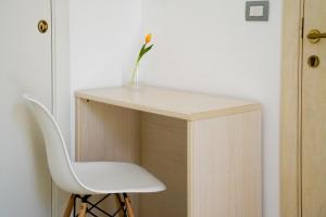 a white chair and a vase with a flower on a desk at B&B Sara in Santa Maria al Bagno