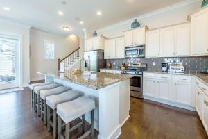 a kitchen with white cabinets and a large island with bar stools at Chalet Mer in Blue Gulf Beach