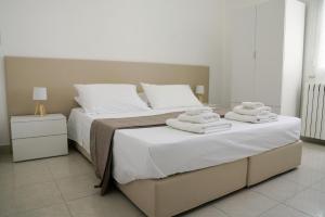 a bedroom with a bed with white sheets and towels at B&B Sara in Santa Maria al Bagno