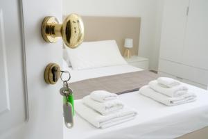 a white room with two beds and a door with towels at B&B Sara in Santa Maria al Bagno