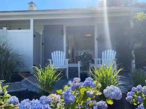 two white chairs sitting on a porch with flowers at Allen Harbor Rentals in Harwich Port