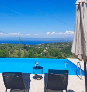 ein blauer Pool mit zwei Stühlen und einem Sonnenschirm in der Unterkunft Apartmaji Meli Pu 2 in Izola