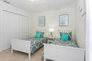 2 bedden in een witte kamer met blauwe kussens bij Enchanting Décor Home with private pool at Storey Lake Resort SL4714 in Kissimmee
