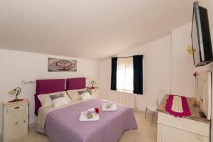 a bedroom with a purple bed and a tv at Casa Vacanze La Magnolia in Viterbo