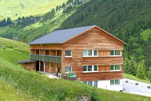 a wooden house on a hill with a mountain at Bergzeit Appartements in Warth am Arlberg