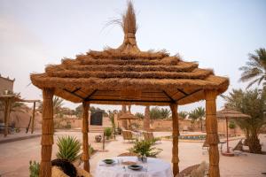 una grande capanna di paglia con tavolo in un cortile di RiadSuerteloca Merzouga a Merzouga