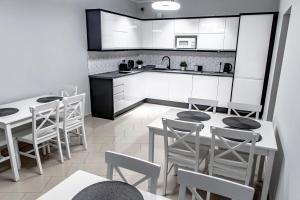 cocina con armarios blancos, mesa y sillas en Willa Amber, en Władysławowo