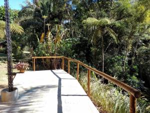 een houten loopbrug naar een tuin met bomen bij Casa Beira Rio - Sítio Terra Surya in Lumiar