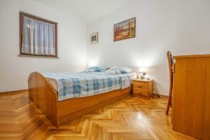 a bedroom with a bed and a wooden floor at Apartment Diracca in Malinska