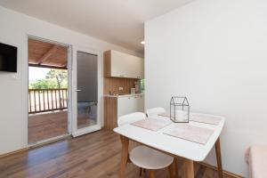 a kitchen and dining room with a white table and chairs at Mobile home Sea Shell in Pašman