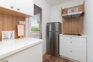 a kitchen with a stainless steel refrigerator and white cabinets at Mobile home Sea Shell in Pašman