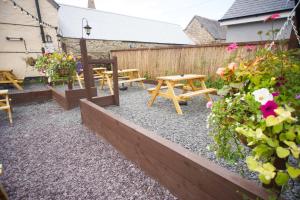 a patio with tables and flowers and a fence at The Dudley Arms in Llandrillo