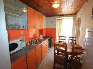 Apartment Tamarut في كريكفينيسا: مطبخ بجدران برتقالية ومغسلة وطاولة