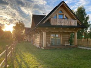 a log cabin with a deck on a yard at Domki Górskie Szlaki in Czarny Dunajec