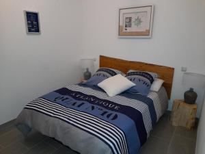 a bedroom with a bed with a blue and white blanket at Ker jolly Maison au cadre naturel sans vis à vis in Plouégat-Guérand