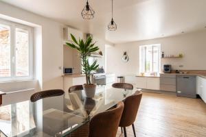 cocina y comedor con mesa de cristal y sillas en Les Nuits Lupéennes, en Lupé