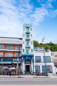 um edifício alto e branco com motos estacionadas em frente em Joi Hospitality - Front Beach em Vung Tau