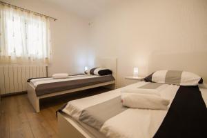 two beds in a small room with a window at Apartments Teskera in Bol