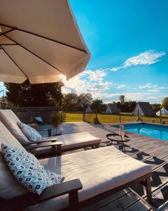 a patio with chairs and an umbrella and a pool at GreenValleyGlamping in Šešče pri Preboldu