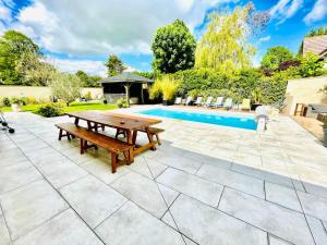 une terrasse avec une table de pique-nique en bois à côté d'une piscine dans l'établissement En toute simplicité, à Lavilletertre